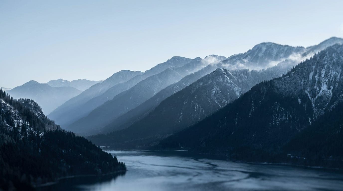 Kühle Alpenlandschaft in Blaustunden-Tönen: gleichmäßig gestaffelte parallele Bergrücken in abgestuften Tönen.